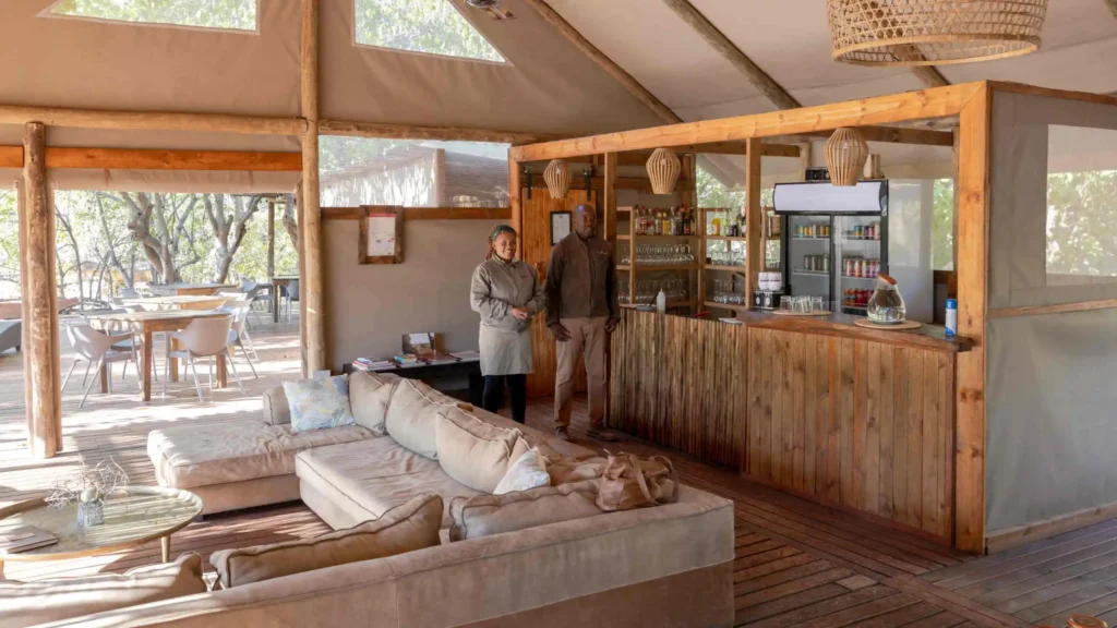 Warm and welcoming bar and lounge area at O Bona Moremi Safari Lodge in Khwai, Botswana â€“ relaxed atmosphere with friendly staff and natural bush views.