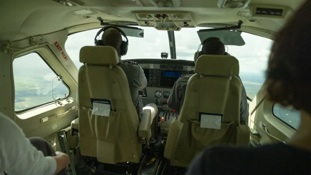 Inside view of the cockpit in a small aircraft flying over the Okavango Delta, showing two pilots at work.