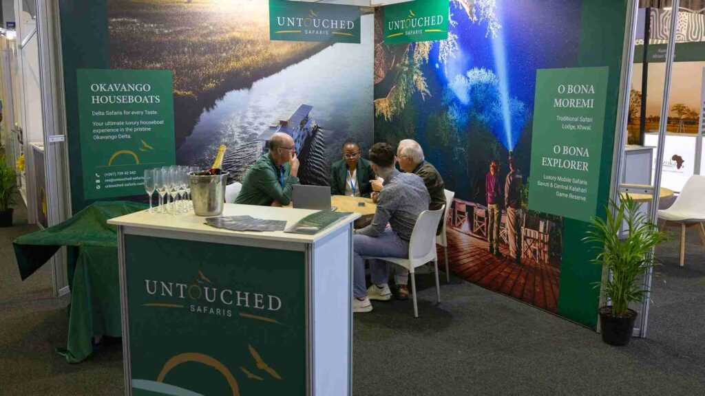Four people sitting at a table at a stand of Untouched Safaris at Indaba 2025.
